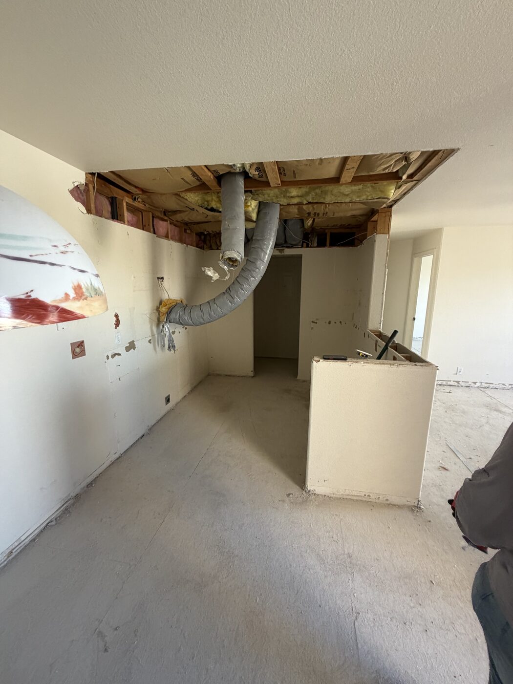 The same kitchen after debris removal, with a swept slab floor and only the framing and ductwork left in place