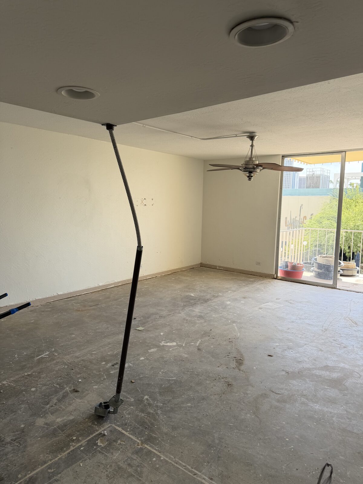 Condo living room stripped of flooring and cabinetry, leaving bare concrete ready for the next trade