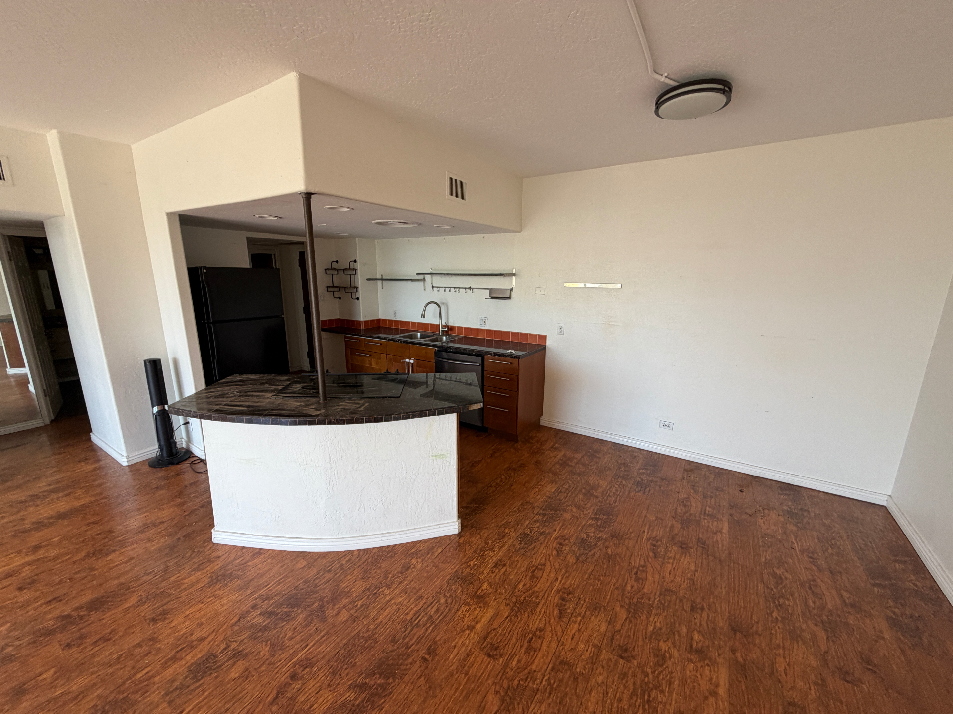 Condo kitchen and open living area fully emptied out, with clean floors and clear counters after a full cleanout