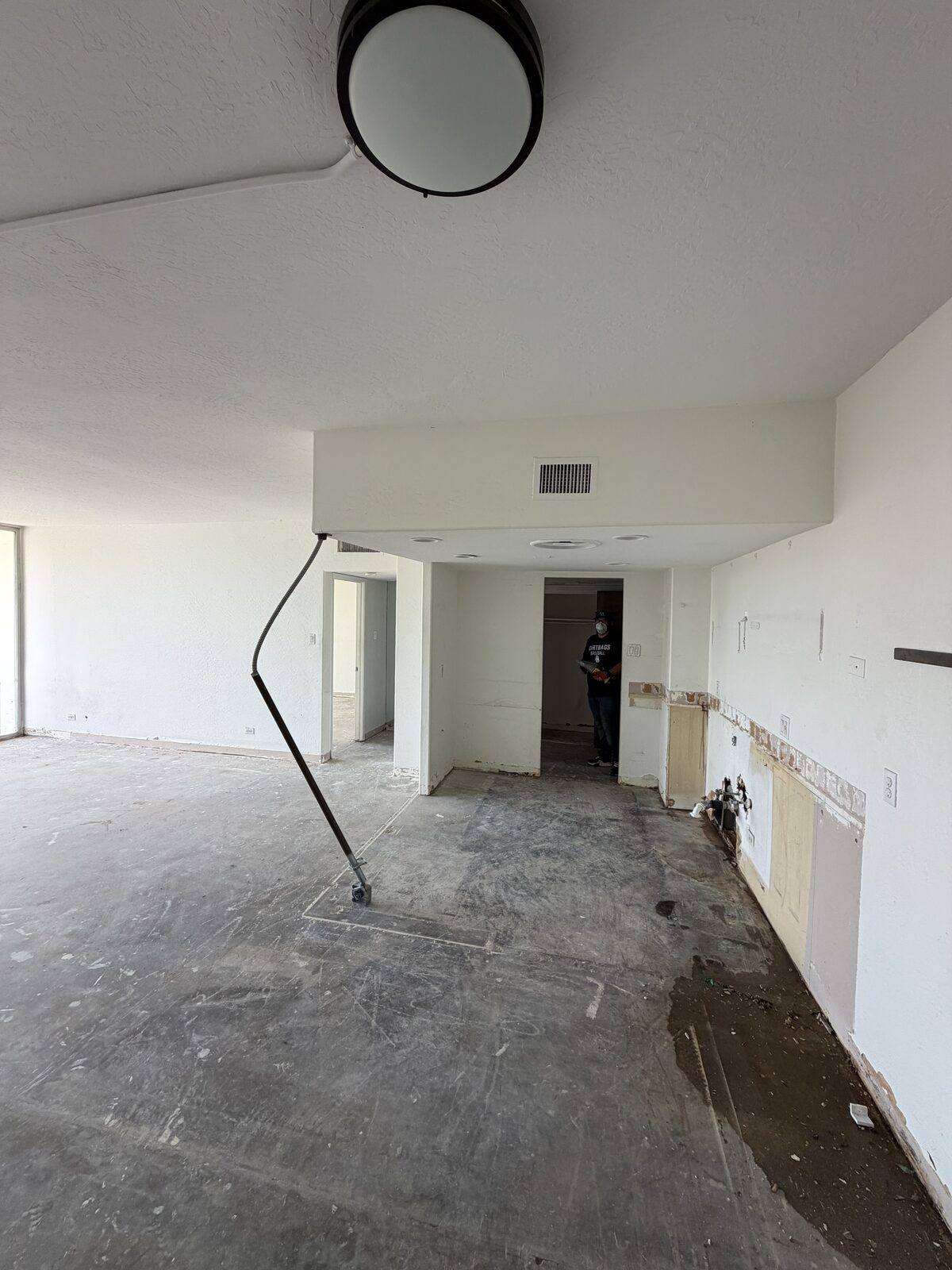 Open condo floor plan after demolition with the kitchen wall opened up and the slab cleaned and cleared